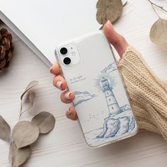 a person is holding an iphone case with a lighthouse on it and some leaves next to them