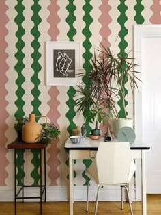 a room with a table, chair and potted plant on the wall next to it