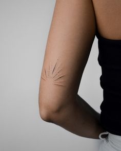 a woman's arm with sunburst tattoo on the back of her arm