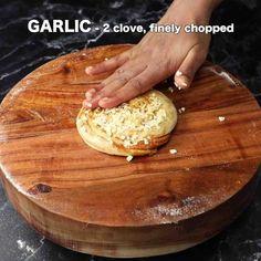 a person is kneading something on top of a wooden board with text overlay that reads garlic 2 clove, finely chopped