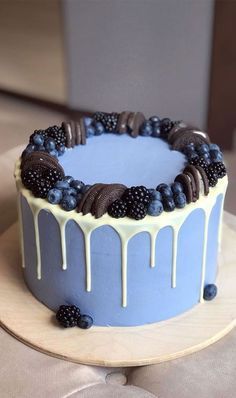 a blue cake with white icing and blackberries