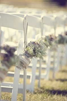 rows of white chairs with flowers in them