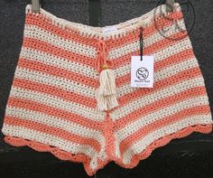 an orange and white crocheted shorts with a tag on it