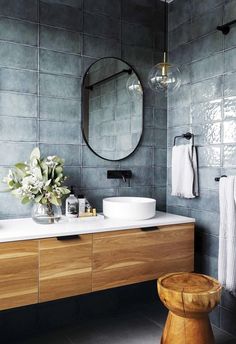 a bathroom with two sinks and a round mirror above the sink is surrounded by greenery