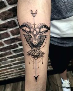 a goat head with an arrow and flower tattoo on the leg