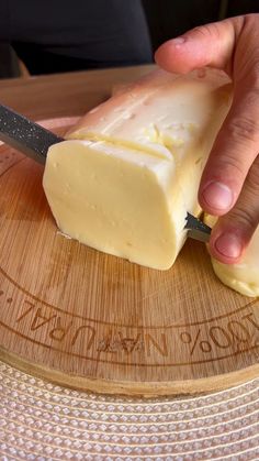 a person cutting cheese on top of a wooden board