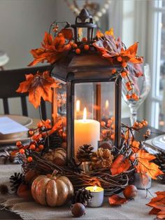 a candle is lit on top of a table decorated with autumn leaves and acorns