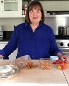 a woman standing in front of a counter with bowls and containers of food on it