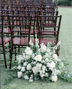 an arrangement of white flowers and greenery on the ground in front of rows of chairs