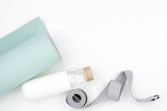 a yoga mat, roll and bottle of water on a white surface with a light blue background