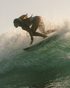 a woman riding a wave on top of a surfboard