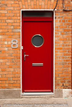 a red door is in front of a brick wall