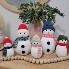 a group of snowmen sitting on top of a wooden table next to a potted plant