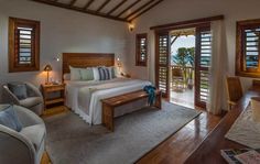 a bedroom with a bed, chairs and windows that look out onto the ocean at night