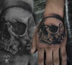 a man's hand with two skulls on it and one skull in the middle