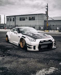 a white nissan sports car parked in front of a building with dark clouds above it