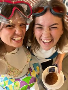 two girls wearing goggles and holding a bowl of food in front of their face