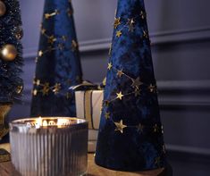 three blue christmas trees with gold stars on them and a lit candle in the middle