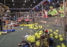 a group of people standing around a room filled with tennis balls