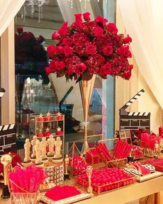 a table topped with lots of red flowers next to a movie slates and popcorn