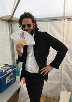 a man in a suit and sunglasses holding a fan