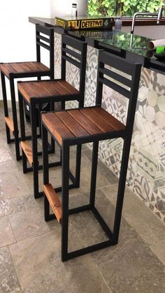 three wooden stools sitting on top of a tiled floor next to a bar counter