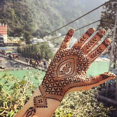 a person's hand with henna on it and mountains in the background,