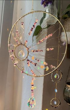 a dream catcher hanging from the side of a wall next to a potted plant