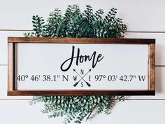 a sign that says home on it next to some green plants and wood planks