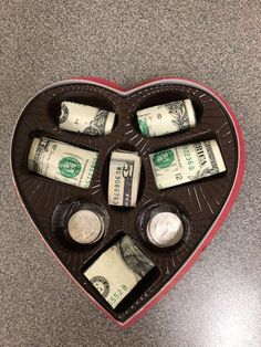 a heart shaped box filled with money on top of a table