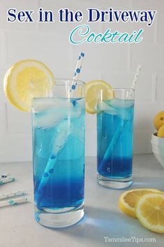 two glasses filled with blue liquid next to lemons