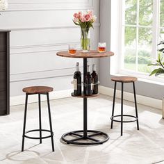 two stools and a table with bottles on it in front of a white wall