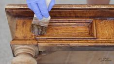 a person in blue gloves is painting a wooden table