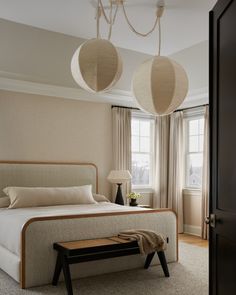 a bed room with a neatly made bed and two lamps hanging above the headboard