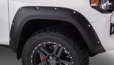 the front end of a white truck with black spoked wheels and tire hubs