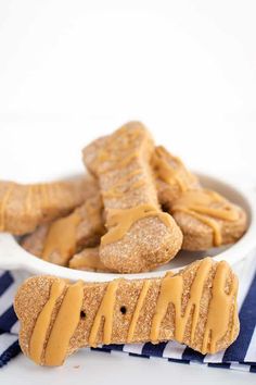 peanut butter dog treats in a white bowl on a blue and white striped napkin next to it