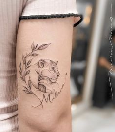 a woman's arm with a small tattoo of a cat and an olive branch