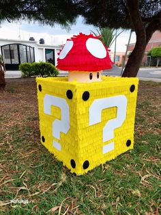 a paper mache box sitting in the grass with a mushroom on it's head