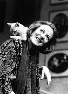 a black and white photo of a woman with a cat on her shoulders, smiling at the camera