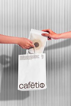 two hands holding a paper bag with the word cafetto on it, and another hand reaching out