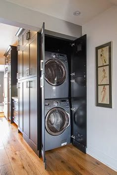 a washer and dryer in a room with wood floors, framed pictures on the wall