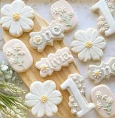 decorated cookies with flowers and the word love are on a cutting board next to some daisies