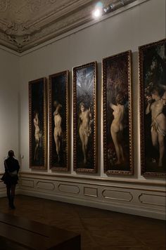 a woman is looking at paintings on the wall