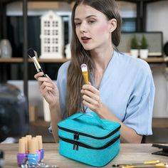 a woman sitting at a table holding a brush and makeup bag in front of her