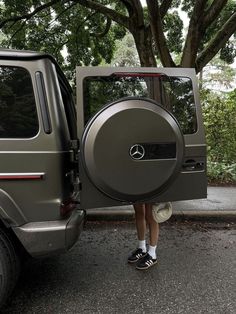 a woman is standing in front of a vehicle with the door open