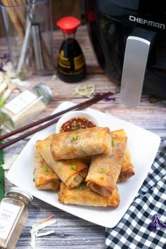 some food is on a white plate with chopsticks next to it and an air fryer in the background