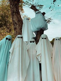 several white cloths hanging from a tree with eyes on them