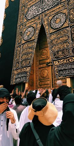 many people are standing in front of an ornate building with gold and black decorations on it