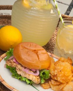 a sandwich and chips on a plate next to lemonade