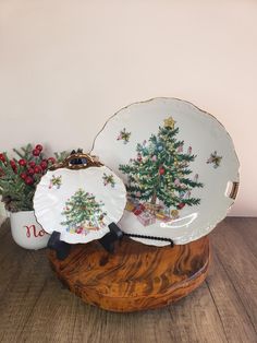 two christmas plates sitting on top of a wooden table next to a potted plant